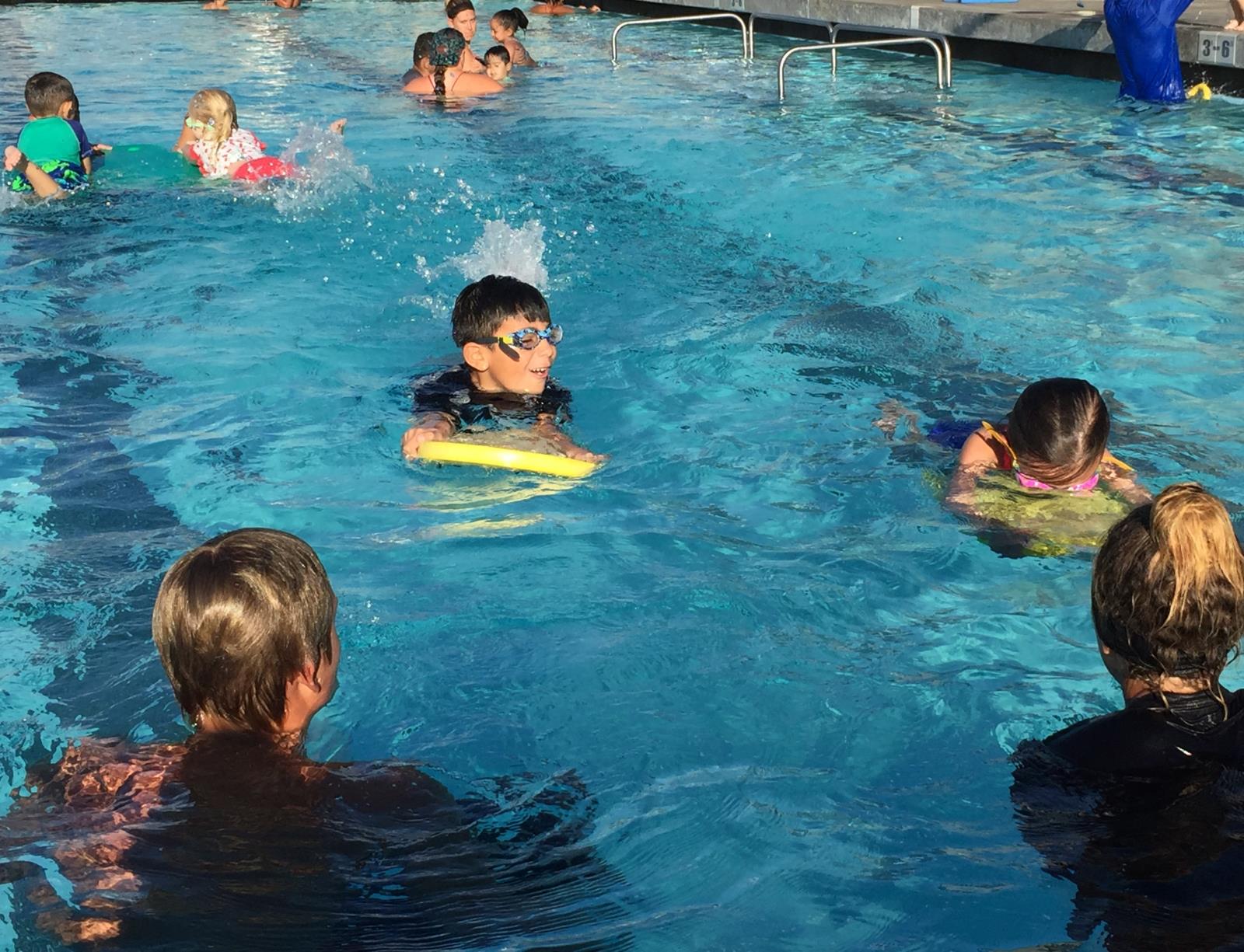 Swim instructors work with two children in the pool