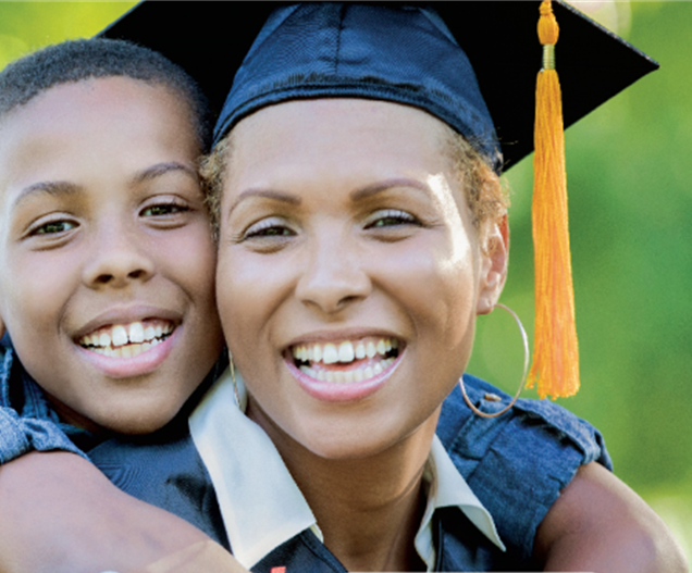 Woman wearing graduation gown with boy on her back both smiling
