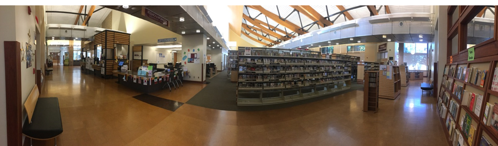A panoramic view of the Tulare Public Library Reference Desk and movie collection. 